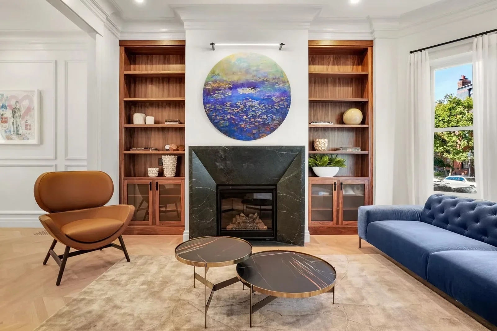 Modern living room with walnut built-in shelving, black marble fireplace, and coffered ceiling