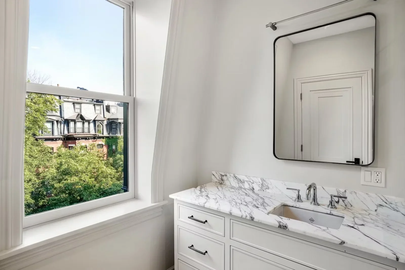Master bathroom with white vanity, marble countertop, undermount sink, and black-framed mirror
