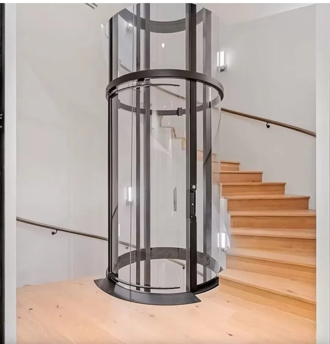 Curved glass residential elevator with dark metal frame and base installed next to wooden stairs