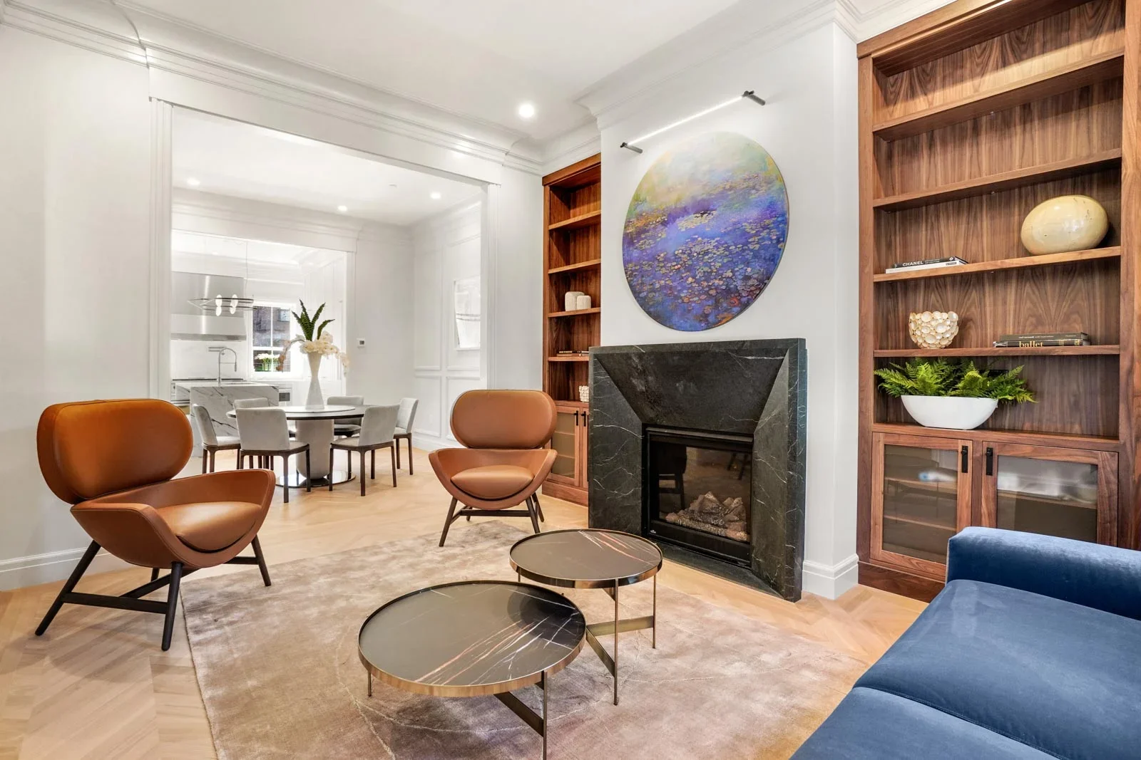 Modern living room with custom wood shelving, marble fireplace, hardwood floors, and contemporary furnishings