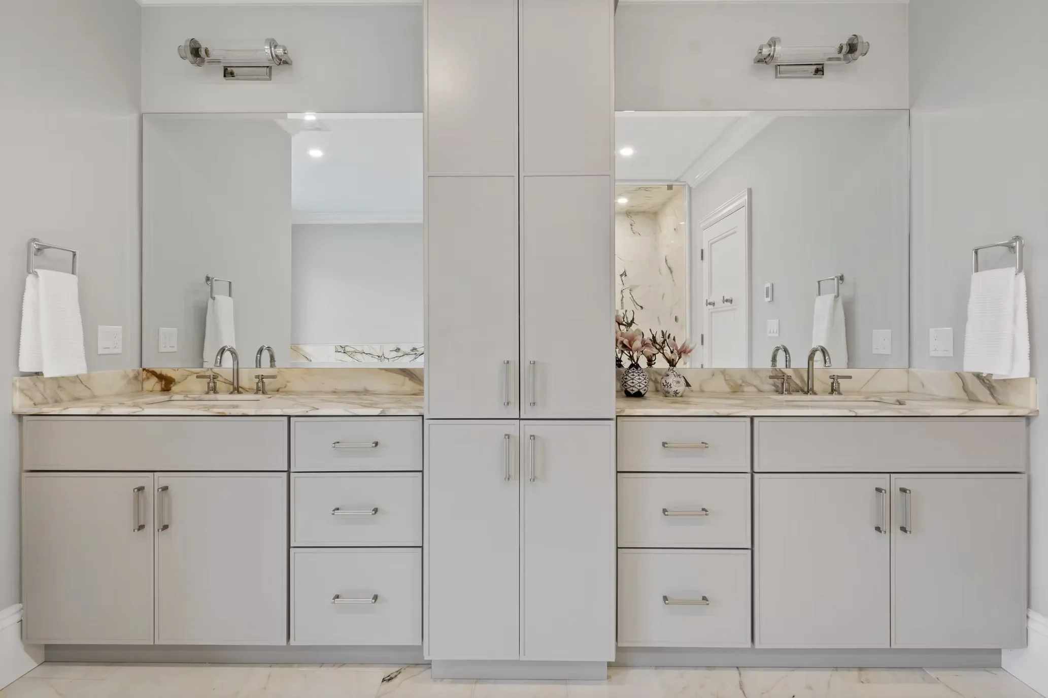 Dual vanity bathroom with marble countertops, white cabinetry, and chrome fixtures
