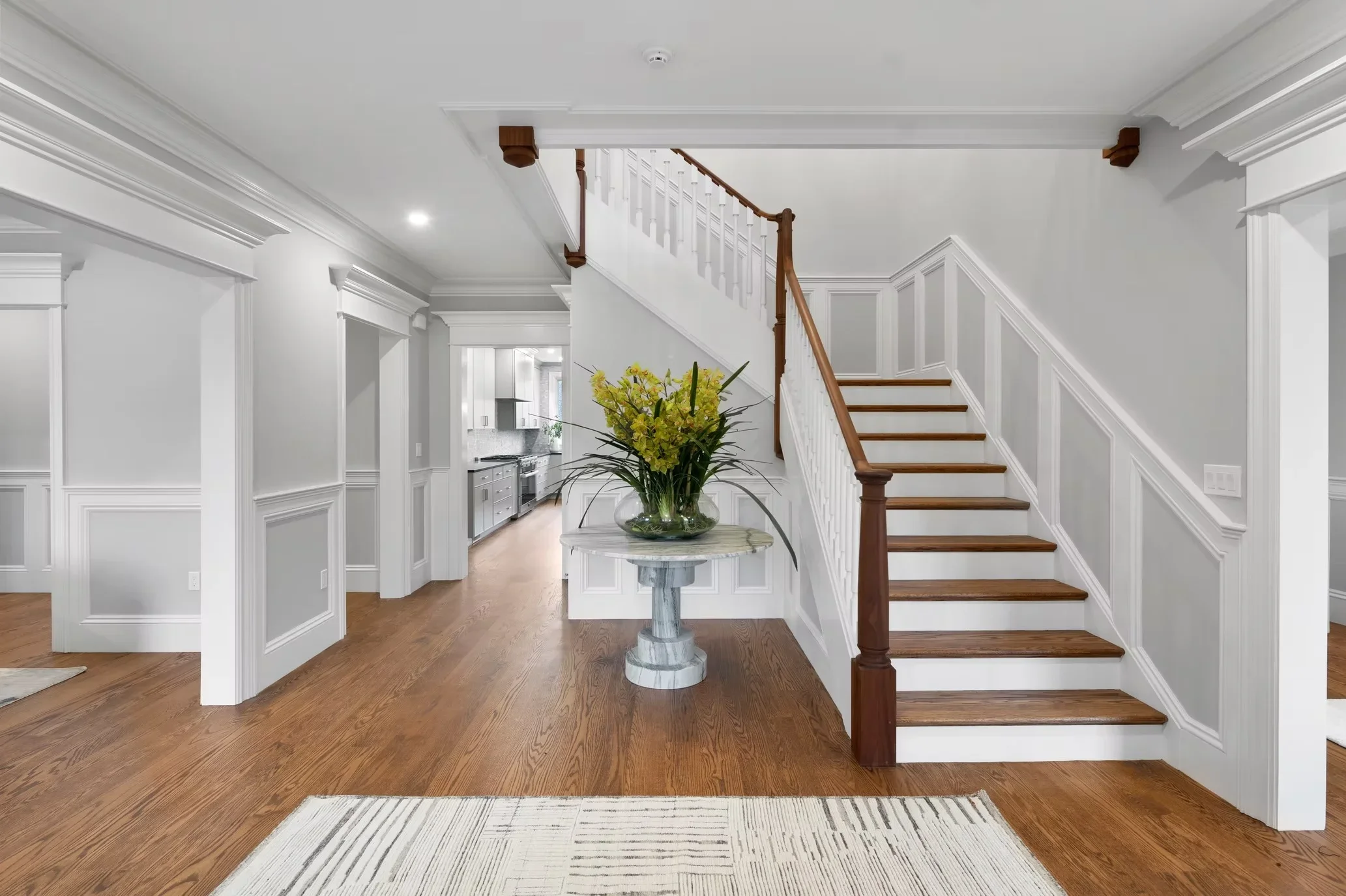 Foyer with wood staircase, white wainscoting, hardwood floors, and recessed lighting