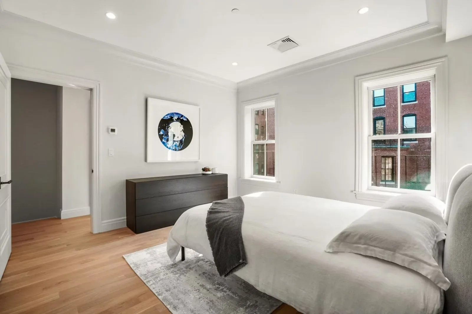 Master bedroom with hardwood floors, white trim, recessed lighting, and large windows