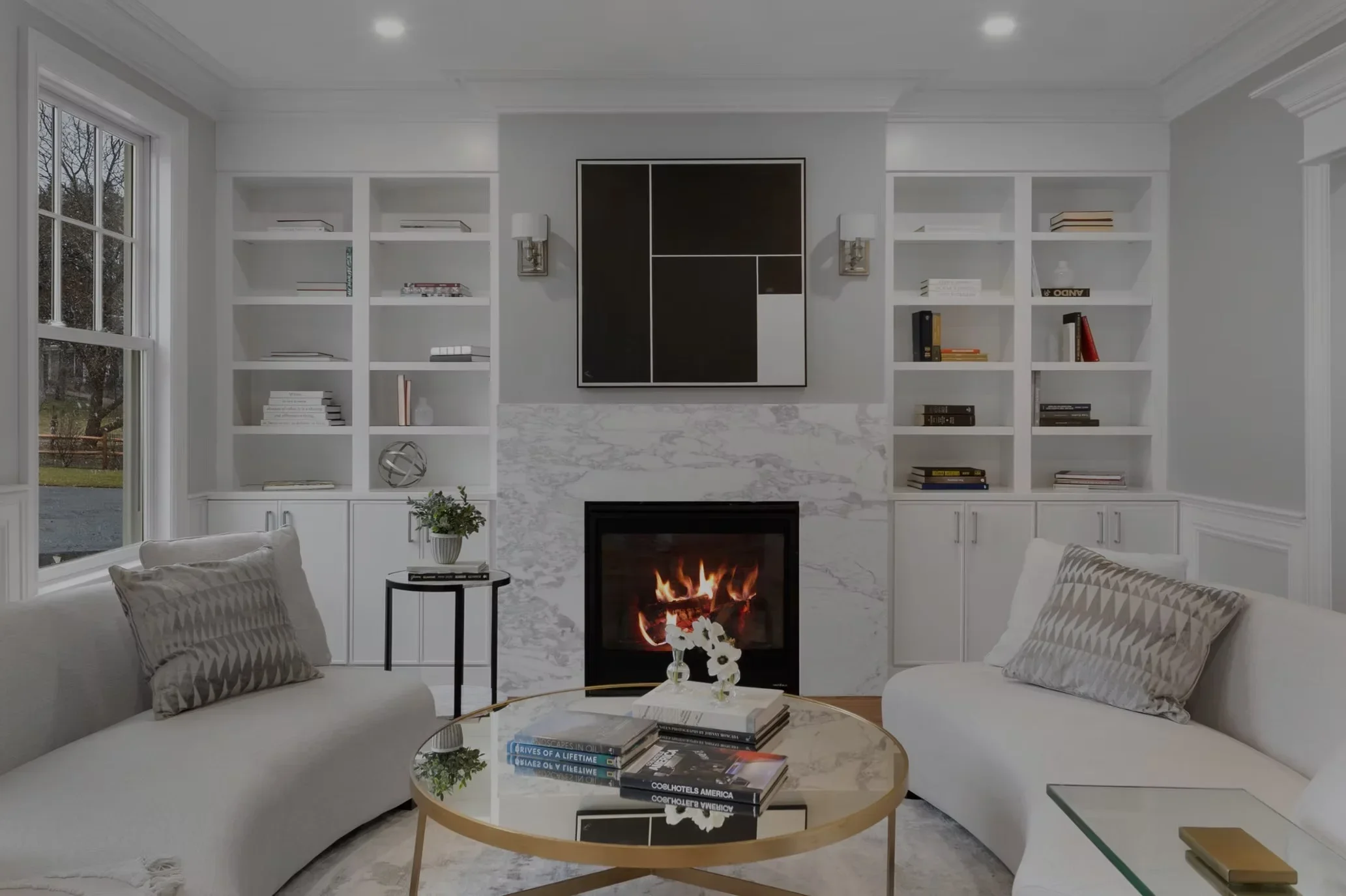 White built-in shelving with marble fireplace wall and black framed artwork in modern living room