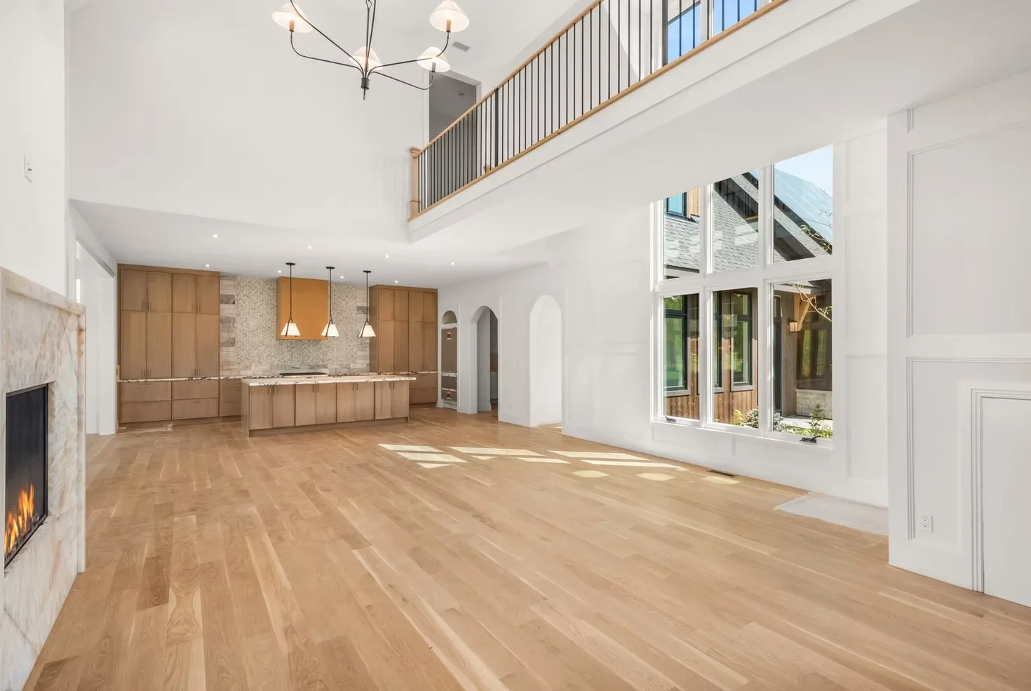 Open concept kitchen with oak cabinetry, hardwood floors, gas fireplace, and two-story mezzanine
