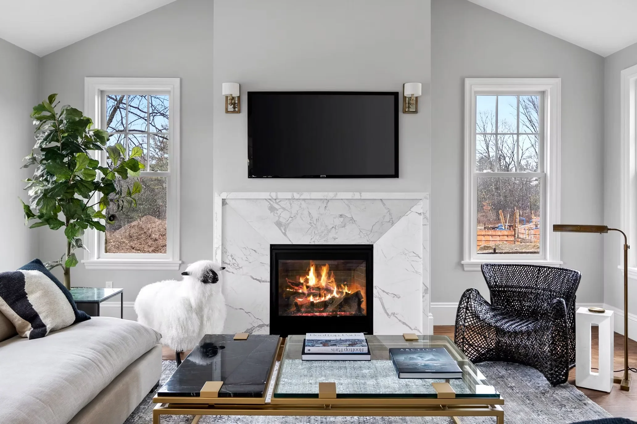 Modern living room with marble fireplace surround, wood-burning stove, mounted TV, and vaulted ceiling with skylights