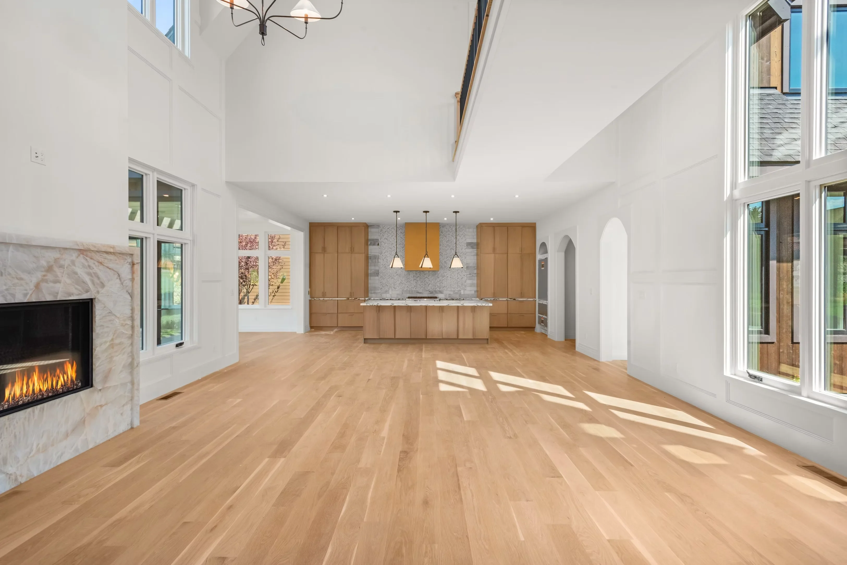 Open concept kitchen with hardwood floors, custom wood cabinetry, marble fireplace, and vaulted ceilings