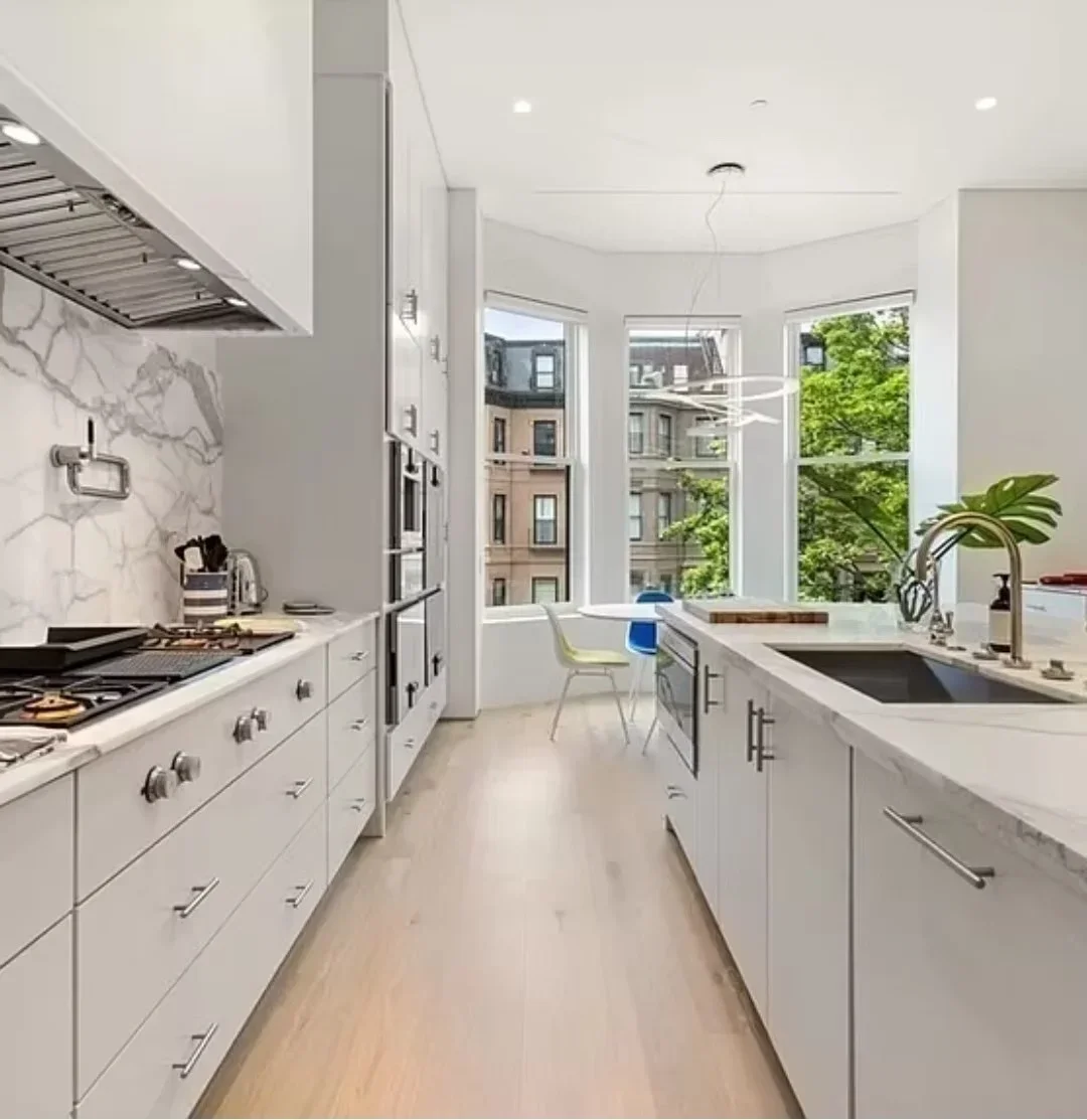 White kitchen with marble backsplash, custom cabinetry, gas range, and quartz counters