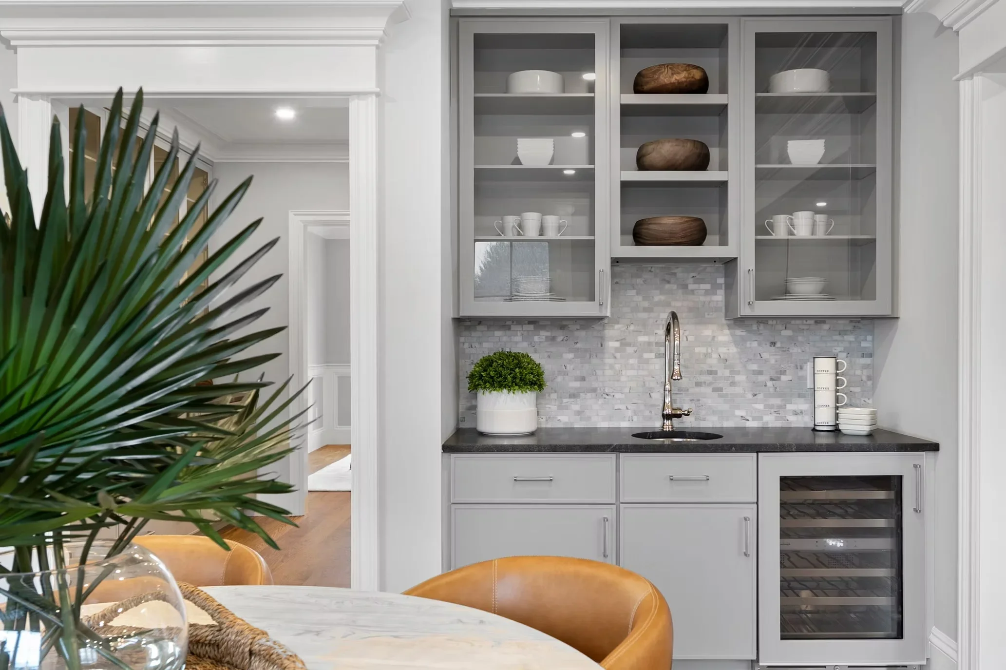 Gray custom cabinets with glass doors, marble subway tile backsplash, dark quartz counters, and built-in beverage cooler