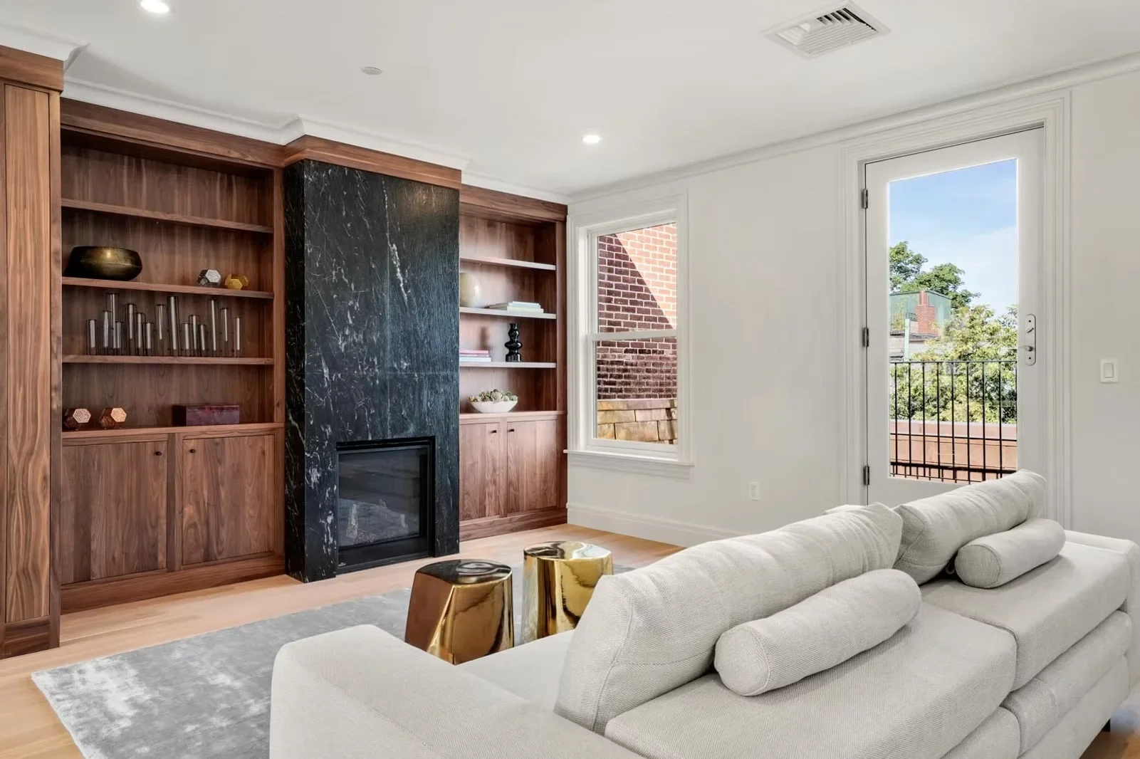 Custom walnut built-in cabinetry with black marble fireplace, recessed lighting, and hardwood floors in modern living room