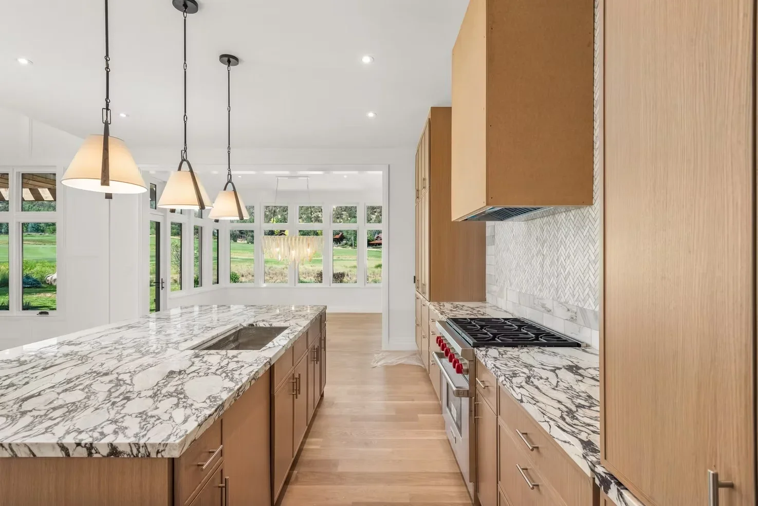 Modern kitchen with marble countertops, wood cabinetry, gas range, and pendant lighting