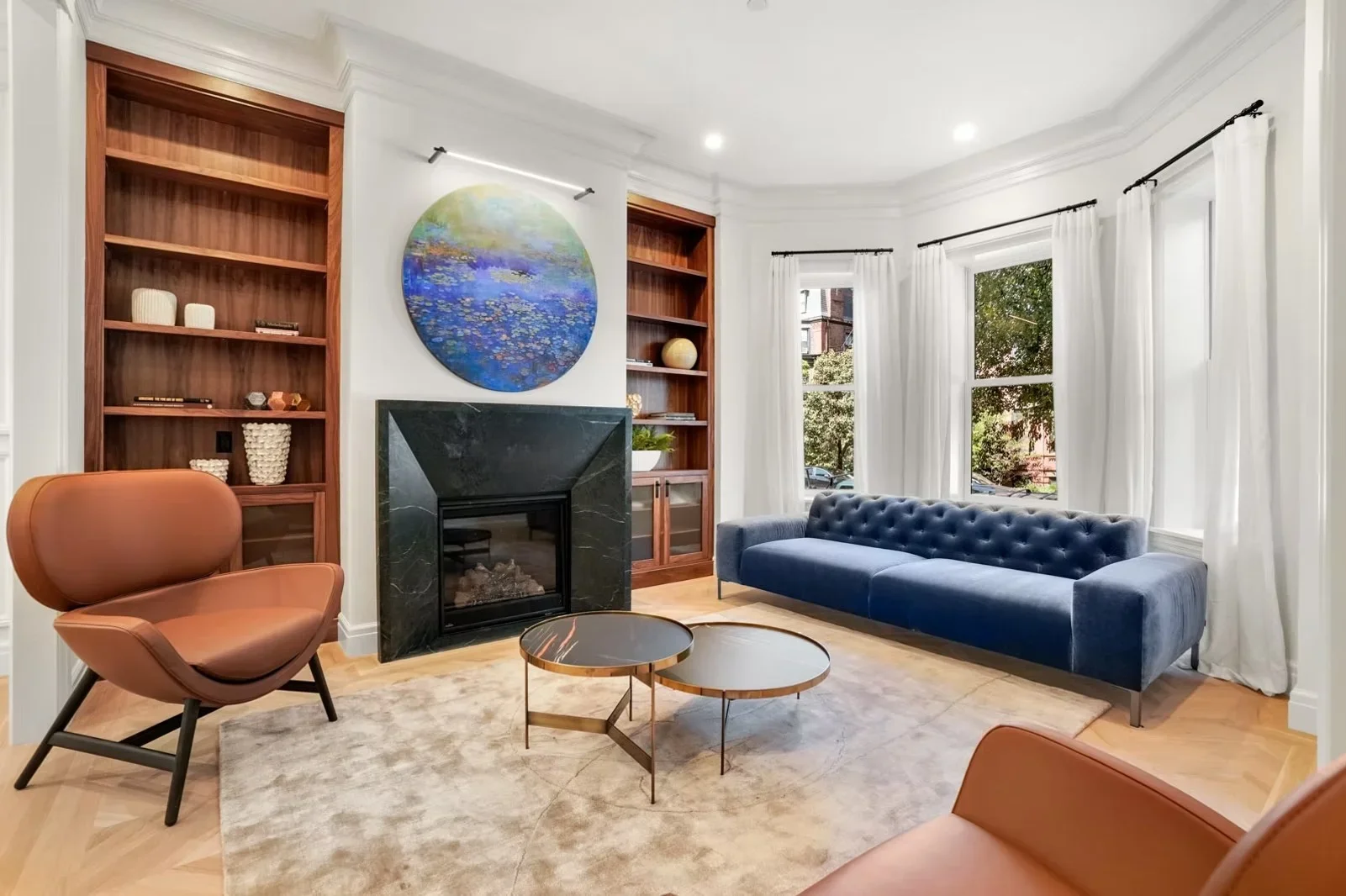 Living room with walnut built-ins, marble fireplace, hardwood floors, and white trim